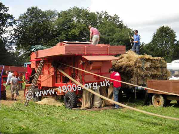 Moving belt connecting the thresher to a traction engine