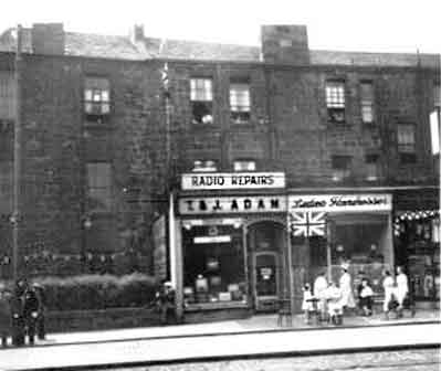 Shops built into the ground floor of a tenement block, mid 20th century