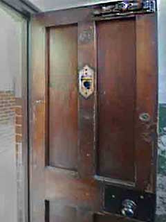 The heavy door to the cell of a casual ward, also known as a dosshouse,
 showing the huge bold at the top and the peep hole to let the 'tramp major' keep an eye on the vagrants.