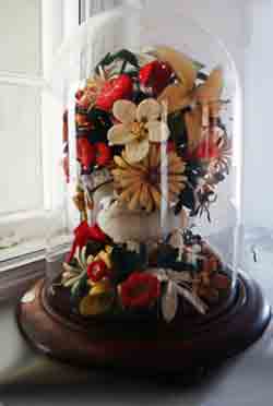 Wax flowers in a glass dome, common on graves in the early 1900s where they would stay for years